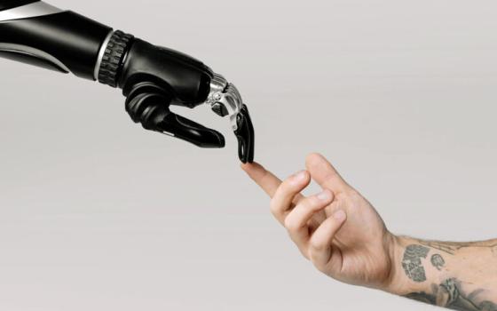 Photograph re-creation of "The Creation of Adam"; human hand reaches out to touch robotic arm.