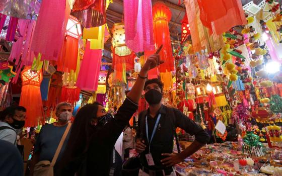 Vibrant stall hung with lanterns, people point and look.