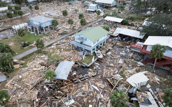 Aerial view of devastated town; ground strewn with wreckage, few buildings remain. 