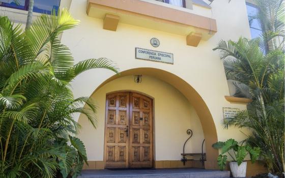 Facade of stucco building, graced by palms.