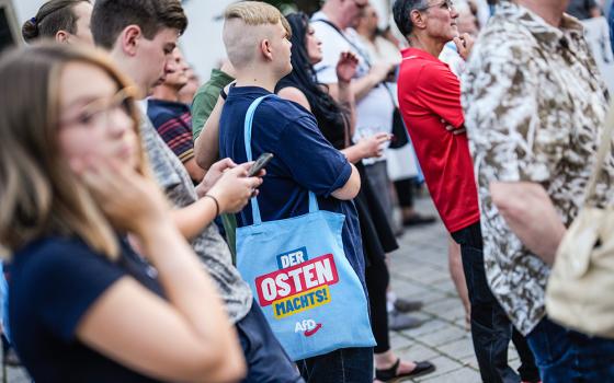 A young man with an AfD bag reading, "The East does it," attends a campaign rally of the far-right Alternative for Germany party in Suhl in the German state of Thuringia Aug. 13. (AP/Markus Schreiber)