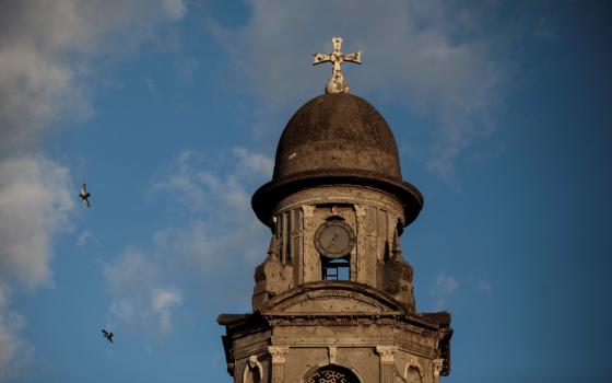 Close-up of stone tower against blue and white sky.