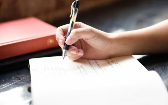 hand with pen, writing in book