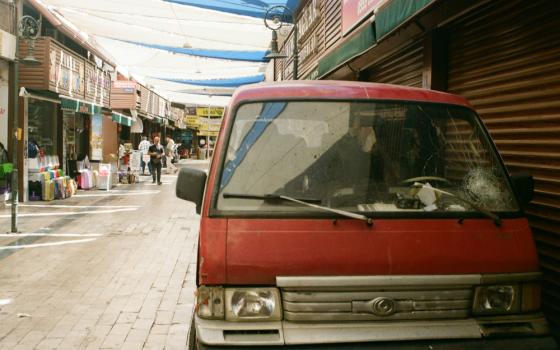 A red van with a cracked windshield parked on the side of the street.