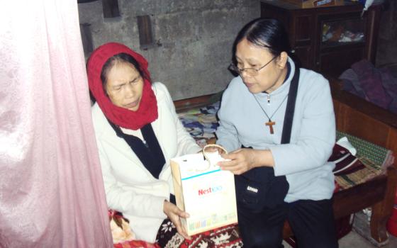 Sr. Mary Vu Thi Ngoc (right) offers a gift to a patient who suffers from domestic abuse on Mar. 6 in Phong Dien district of Thua Thien Hue province, Vietnam. (Joachim Pham)