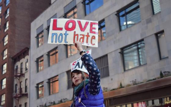 Child holds sign: Love not hate.