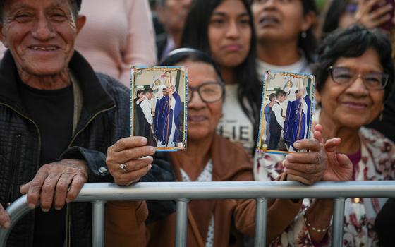Victoria Herrera, a Chiclayana, holds photos of her grandchildren with Bishop Robert Prevost, during an outdoor Mass on May 10, where thousands prayed for Prevost's success in his new role as Pope Leo XIV. (GSR photo/Manuel Rueda)