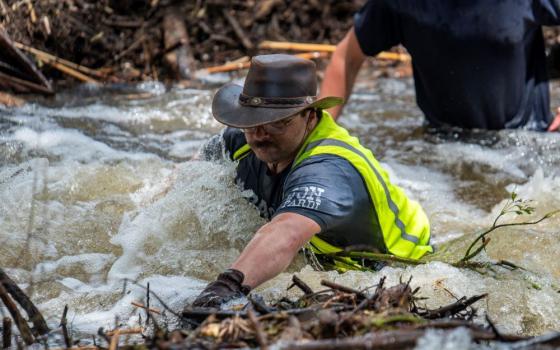 Brandon Myrtle stands in the Guadalupe River as he tries to clear debris in Center Point, Texas, July 11 following catastrophic floods. More than 130 people — including at least 28 children— died after devastating flooding in the Texas Hill Country that began early on the Fourth of July.  (OSV News/Reuters/Sergio Flores)