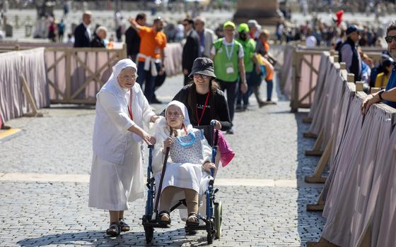 A religious sister and a volunteer help a sister in a wheelchair get to her place in St. Peter's Square at the Vatican for a session of prayer and catechesis during the Jubilee of People with Disabilities April 29, 2025. (CNS/Pablo Esparza)