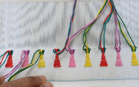 Small red, pink and yellow patterns incorporated into Lourdes Munguia's weaving work done on a loom (Courtesy of Lourdes Munguia) 