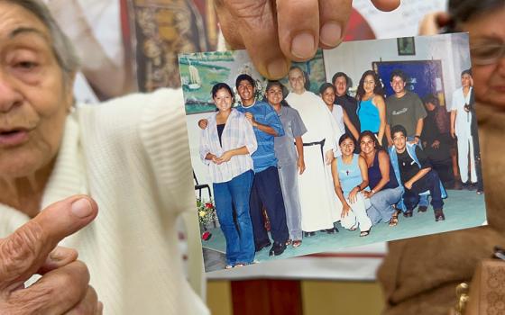 Socorro Cassaro holds up a picture of Augustinian Fr. Robert Prevost with a group of young people at Our Lady of Montserrat Parish in Trujillo, Peru. Prevost, the future Pope Leo XIV, served as parochial administrator of the parish from 1992 to 1999. (NCR photo/Justin McLellan)