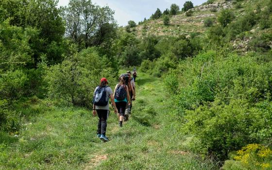 A group of people hiking a trail up a hill (Unsplash/Art of Hoping)