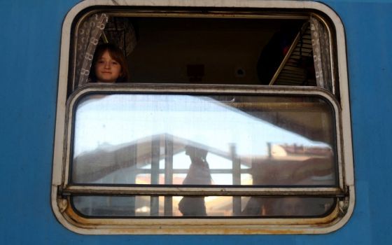 A Ukrainian girl from Kharkiv, Ukraine, looks out a train window bound for Warsaw, Poland, March 23 with people fleeing Russia's ongoing war in Ukraine. (CNS photo/Hannah McKay, Reuters)