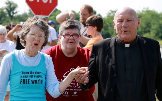 Oblate Fr. Carl Kabat, right, holds the hand of organizer Jane Stoever, left, as they lead protesters across the property line at the National Nuclear Security Administration's Kansas City Plant July 13, 2013, in Kansas City, Missouri. 