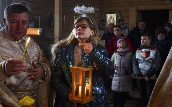 A girl holds a candle during a Christmas service at the Ukrainian Greek Catholic Church of the Holy Prophet Elijah in Kramatorsk, not far from a front line with Russia-backed separatists in eastern Ukraine, Dec. 25, 2021. (AP/Andriy Andriyenko)