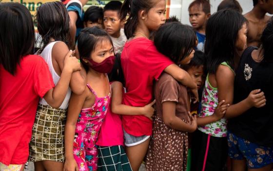 Children wait in line for food from an unidentified relief program in a poor section of Manila, Philippines, Jan. 21, 2021, during the COVID-19 pandemic. (CNS/Reuters/Eloisa Lopez)