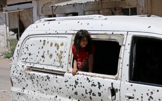 A girl in Daraa, Syria, looks out from a bullet-riddled bus July 9, 2017. Syria's civil war has now entered its 10th year. (CNS/Reuters/Alaa Al-Faqir)