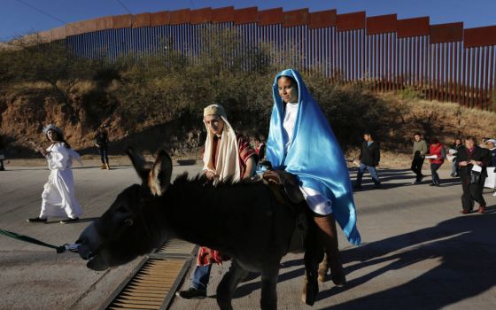 Saul Gonzalez and Kenia Salas play the parts of Joseph and Mary as they make their way along the international border fence in Nogales, Mexico, Dec. 20, 2015, as they participate in a traditional Mexican Las Posadas. (CNS photo/Nancy Wiechec)