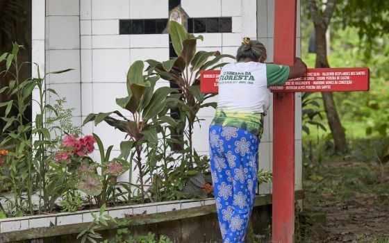 Antonia Silva Lima prays at the grave of U.S.-born Sister Dorothy Stang in Brazil. The red cross bears the names of local rights activists murdered since her killing. (CNS Photo/Paul Jeffrey)