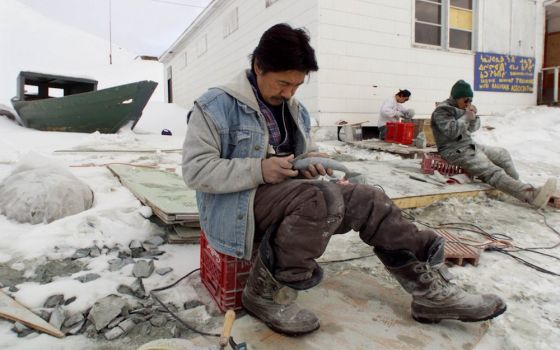 An Inuit carver works on his art on the shore of Frobisher Bay in the Canadian town of Iqaluit, Nunavut. (CNS photo/Shaun Best, Reuters)