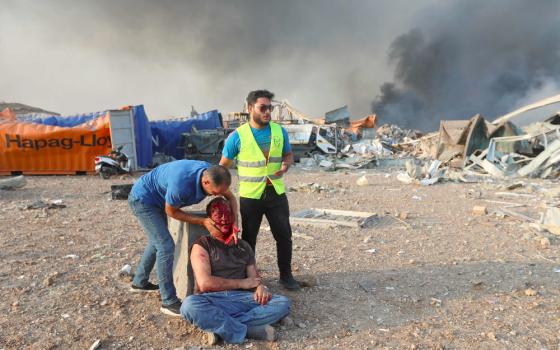 An injured man is aided following explosions at the Beirut, Lebanon, port on Aug. 4, 2020. (CNS photo/Mohamed Azakir, Reuters)