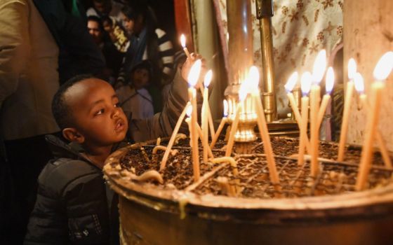 An Ethiopian boy lights a candle in the grotto in the Church of Nativity in Bethlehem, West Bank, Dec. 15, 2018. The church is built on the site believed to be where Jesus was born. (CNS/Debbie Hill)