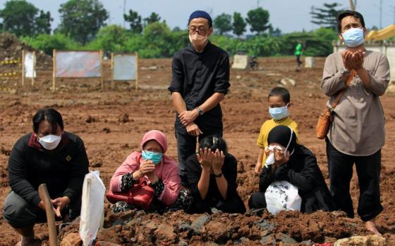 Relatives of a 31-year-old man who died after contracting COVID-19 pray after his funeral June 21 at a cemetery provided by the government for victims of the virus in Jakarta, Indonesia. (CNS/Reuters/Ajeng Dinar Ulfiana)