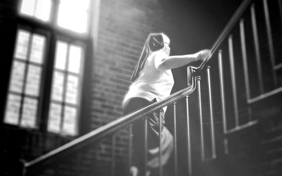 Felician Sr. Mary Ann Smith climbs a staircase in the Felician Sisters' convent in Livonia, Michigan, in June 2020 in this photo illustration. (GSR illustration/Dan Stockman)