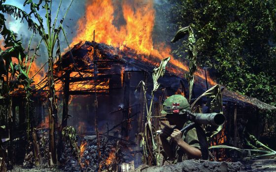 Pfc. Raymond Rumpa of St. Paul, Minnesota, in Mỹ Tho, Vietnam, a Viet Cong base camp burning April 5, 1968 (National Archives/U.S. Army/Dennis Kurpius)