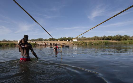 Haitian immigrants make their way along a rope suspended above the Rio Grande on their way to the United States Sept. 22. (Nuri Vallbona)