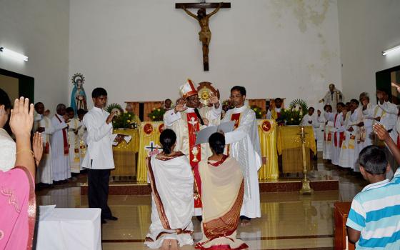 Srs. Sujata Jena and Goretti Nayak receive solemn blessings from Archbishop John Barua during their final vows as members of the Congregation of the Sacred Hearts of Jesus and Mary on Oct. 11, 2014, at St. Vincent Catholic Church in Bhubaneswar, Odisha