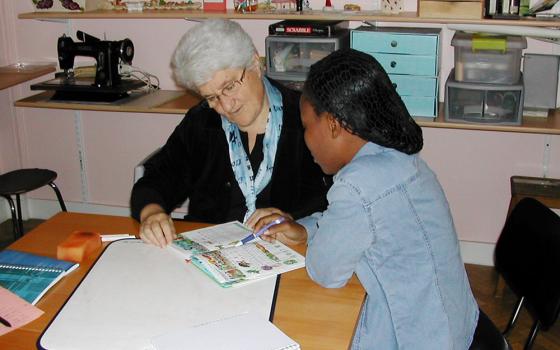 Good Shepherd Sr. Marie-Hélène Halligon, left, teaches the French language to a survivor of trafficking. (Courtesy of Marie-Hélène Halligon)