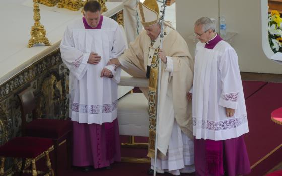 Pope Francis is helped walking as he celebrates the canonization mass for ten new saints in St. Peter's Square at The Vatican, May 15, 2022. (AP Photo/Gregorio Borgia)