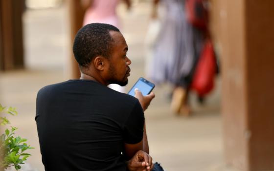 A man checks his mobile phone in Harare, Zimbabwe, in January. (Newscom/Reuters/Philimon Bulawayo)