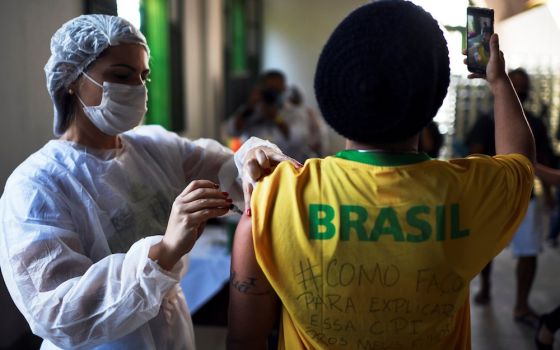 A health care worker administers a dose of Johnson & Johnson COVID-19 vaccine to a resident taking a selfie in Rio de Janeiro July 10. The Brazilian bishops' conference is urging an impartial investigation of government COVID-19 vaccine purchases. (CNS ph