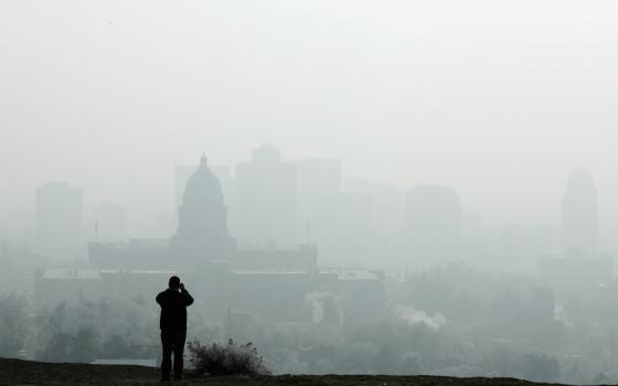 A man stops to take a picture of the Utah State Capitol and buildings that are shrouded in smog in downtown Salt Lake City Dec. 12, 2017. (CNS/Reuters/George Frey)