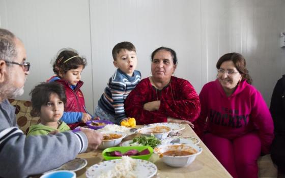 Habiba Daud, second from right, and her family have lunch Dec. 2015 in their trailer at Ashti 2, a camp for internally displaced people in Irbil. The family is from a northern Iraq town overun by the Islamic State group in August 2014. (CNS/Oscar Durand)