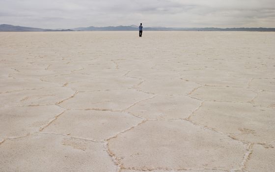 A person stands on the salt flat Salar de Arizaro, in Salta province, Argentina. In Salta and Jujuy provinces, Indigenous communities, whose livelihood depends on the extraction of salt from great deposits, oppose lithium mining, which directly impacts th