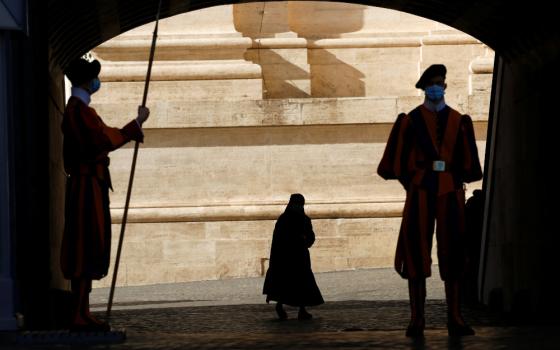 Swiss Guards stand at attention as a nun passes by at the Vatican Nov. 9, 2020. (CNS/Reuters/Remo Casilli)