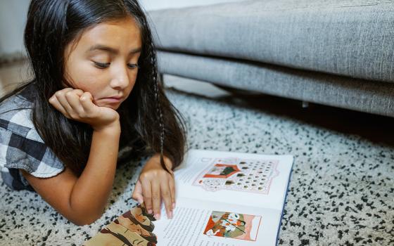 A child reads a sample of "The Book of Belonging." (Photo by Daniel Ebersole)