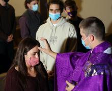 Father Andy Hammeke, associate pastor of St. Mary, Queen of the Universe in Salina, Kans., places ashes on Kansas Wesleyan University students during Ash Wednesday Mass in Fitzpatrick Auditorium Feb. 17, 2021, amid the coronavirus pandemic. 