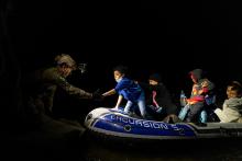 Migrants seeking asylum in the U.S. attempt to get off an inflatable raft with the help of a Texas Ranger officer April 5, 2021, in Roma, Texas, after they crossed the Rio Grande from Mexico. (CNS/Go Nakamura, Reuters)