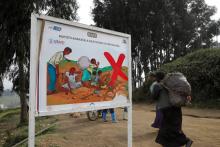 Women in Rubaya, Congo, walk past a sign warning against child labor.