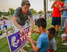 A woman helps two young boys light candles during a "Value Them Both" sidewalk vigil in Olathe, Kansas, Aug. 1. 