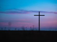 Cross seen in field during sunrise or sunset (Unsplash/Aaron Burden)