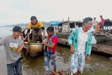 Men in a community on the Marañón River in Peru's Amazon region unload a pot of water they have drawn from the middle of the lake, the community's main water source. (Photo by Barbara Fraser)