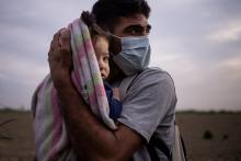 A migrant from Honduras cradles his daughter from the early morning cold and wind after crossing the Rio Grande into La Joya, Texas. Climate change is an underlying cause of migration from Central America and other regions of the world. (CNS photo/Adrees 