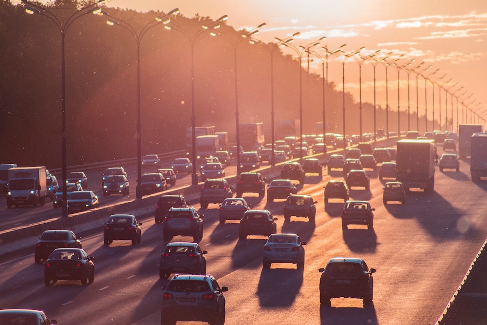 Five lanes of traffic in both directions on divided highway at sunrise or sunset