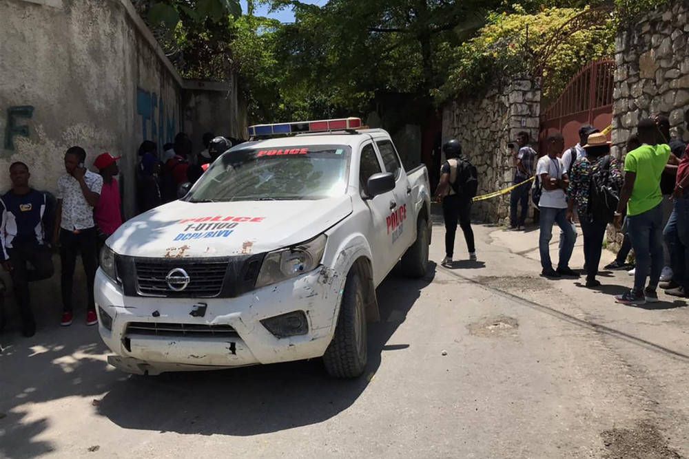 People stand next to a police car and a yellow police cordon near the residence of Haitian President Jovenel Moïse near Port-au-Prince July 7. The president was assassinated in an early morning attack at his home, the prime minister said. (CNS/Reuters/Est