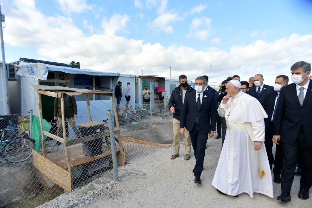 Refugees stand outside their shelters as Pope Francis visits the government-run Reception and Identification Center Dec. 5 in Mytilene, Greece. (CNS/Vatican Media)